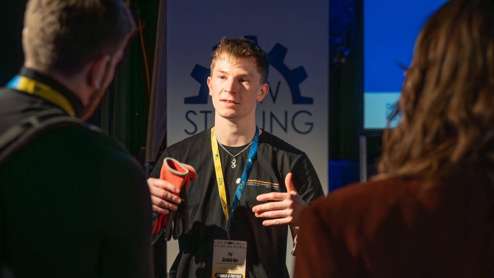 Ein Mitglied der THW-Jugend in einer Gesprächssituation mit zwei Menschen.